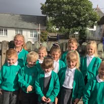 A picture of four children cutting and sticking coloured shapes onto paper